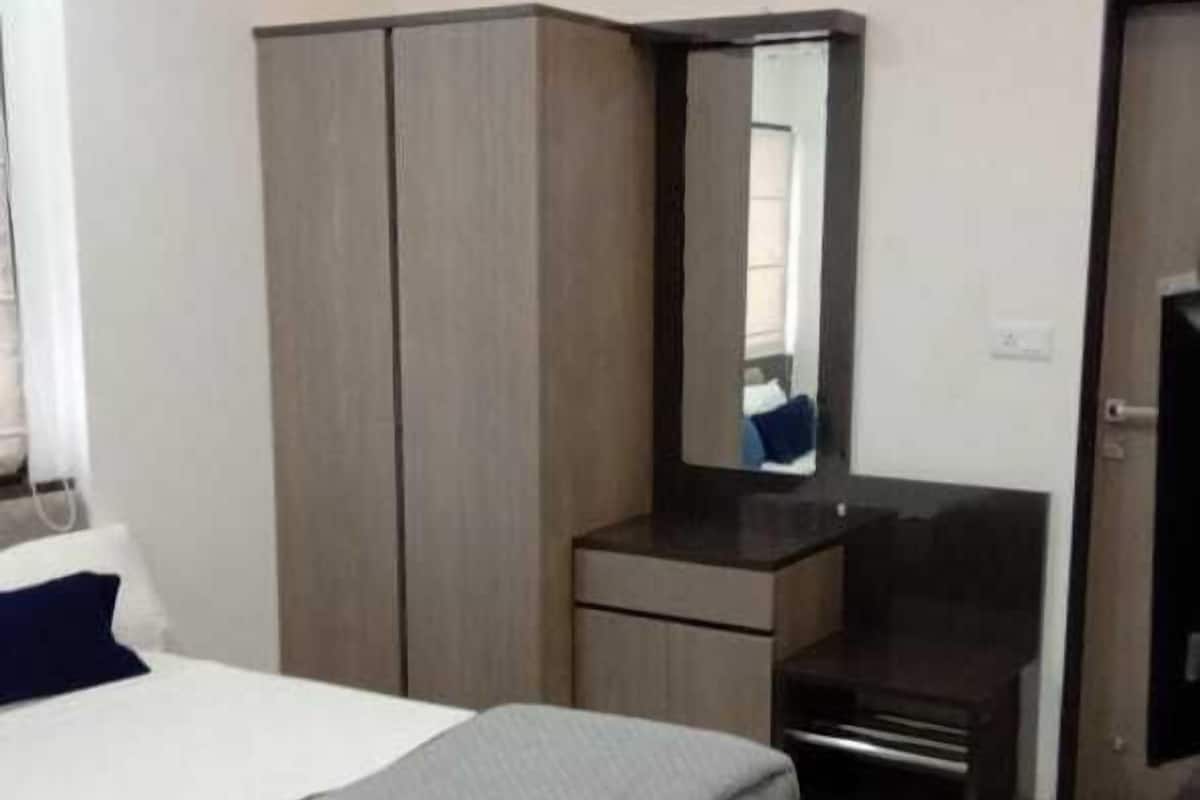 A modern hotel room with a bed, a wardrobe, a desk, and a television.