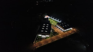 Vista aérea de un edificio con varias secciones, que incluye una amplia zona cubierta con escalones y un edificio más pequeño contiguo.