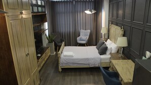 Une chambre à coucher comprenant un lit, une chaise, un bureau, une lampe et une armoire.