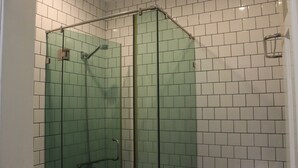 Une douche entièrementClose avec des parois en verre, une poignée en métal et une porte en verre.