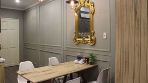 Une salle de conférence avec une table en bois, des chaises blanches, un grand miroir décoratif et un luminaire suspendu.