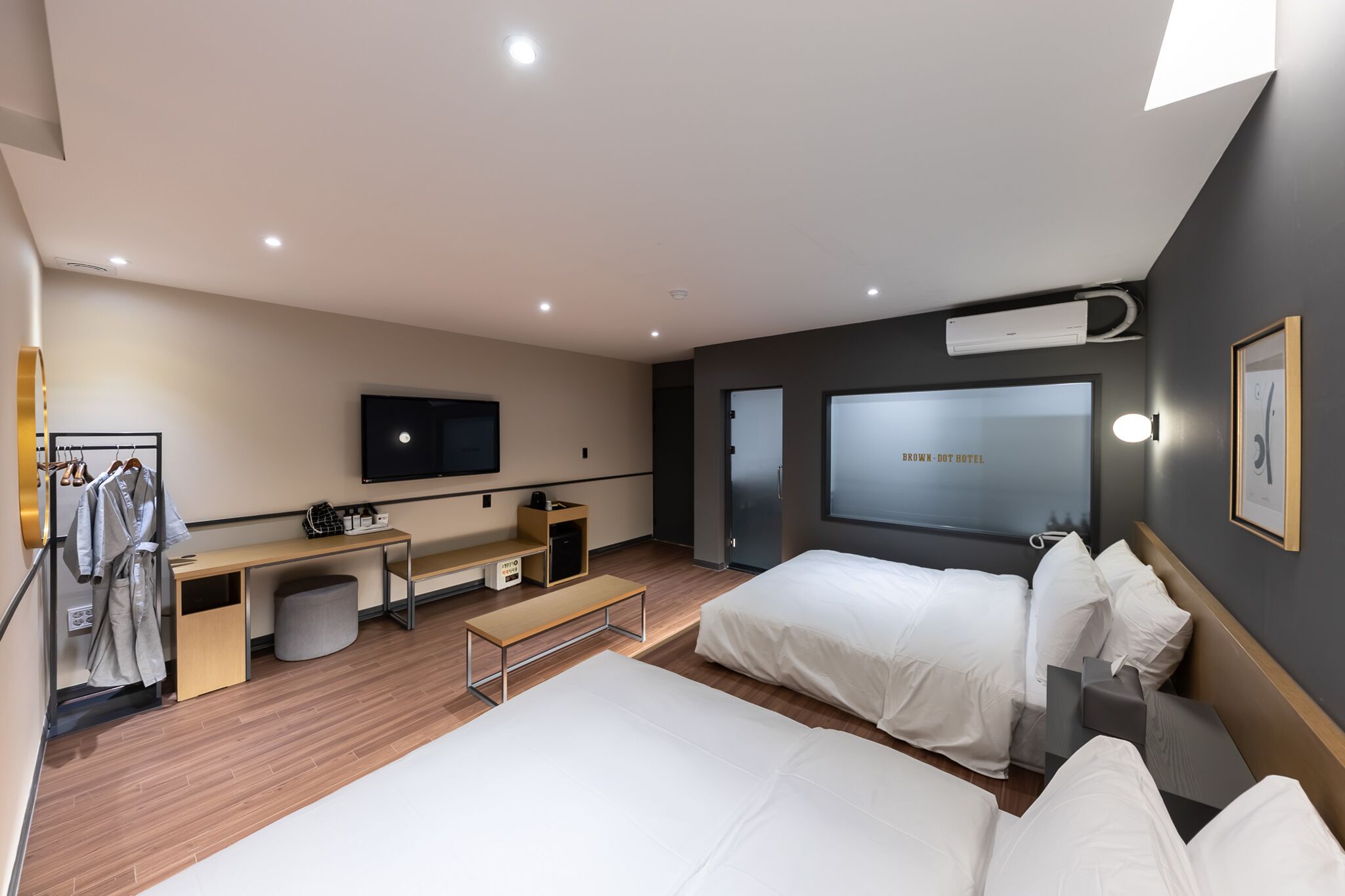 Et moderne hotelværelse med to senge, et skrivebord, et fjernsyn og et stort vindue.
