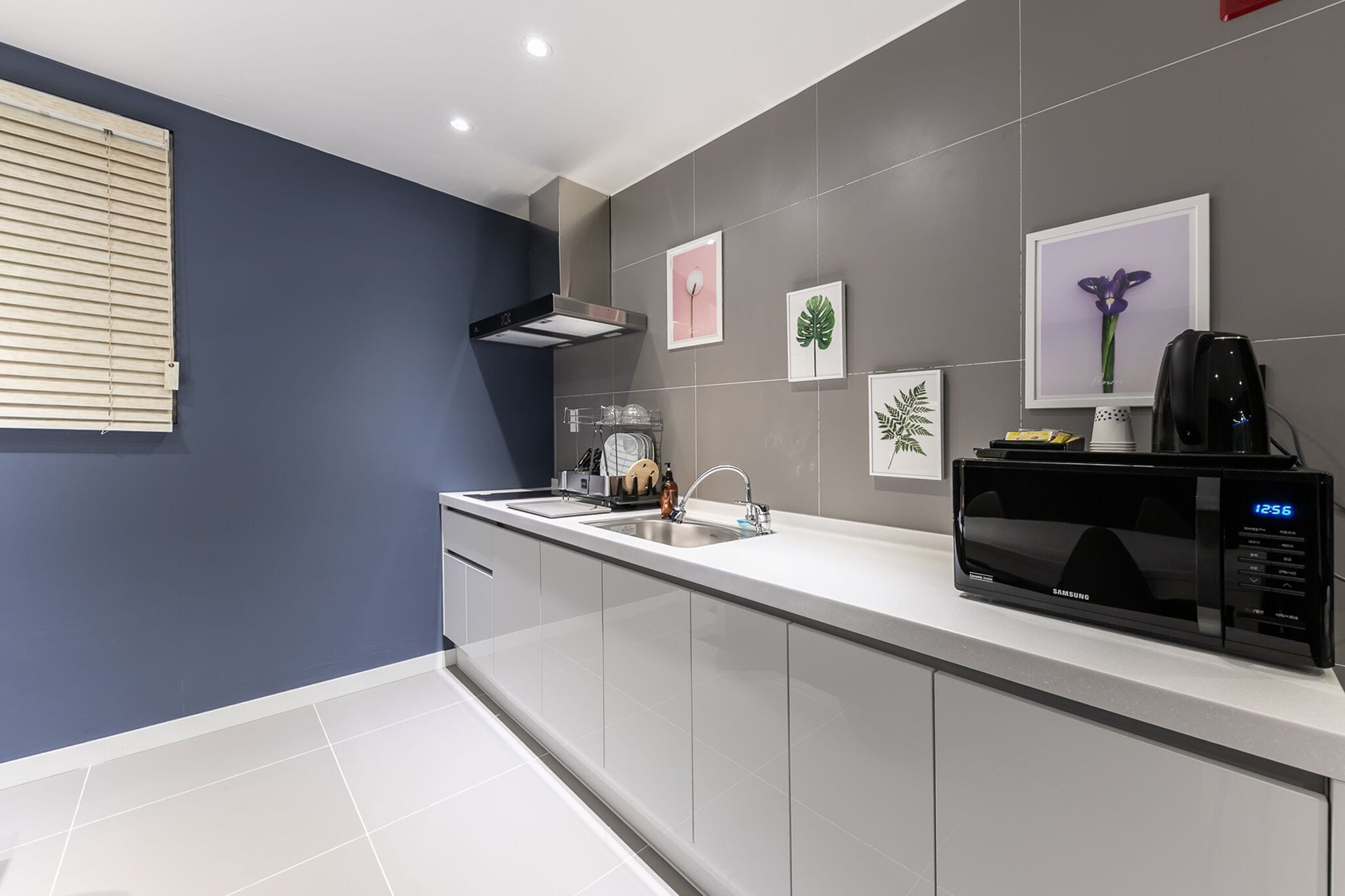 A modern kitchen with a white countertop, grey backsplash, and a black microwave.