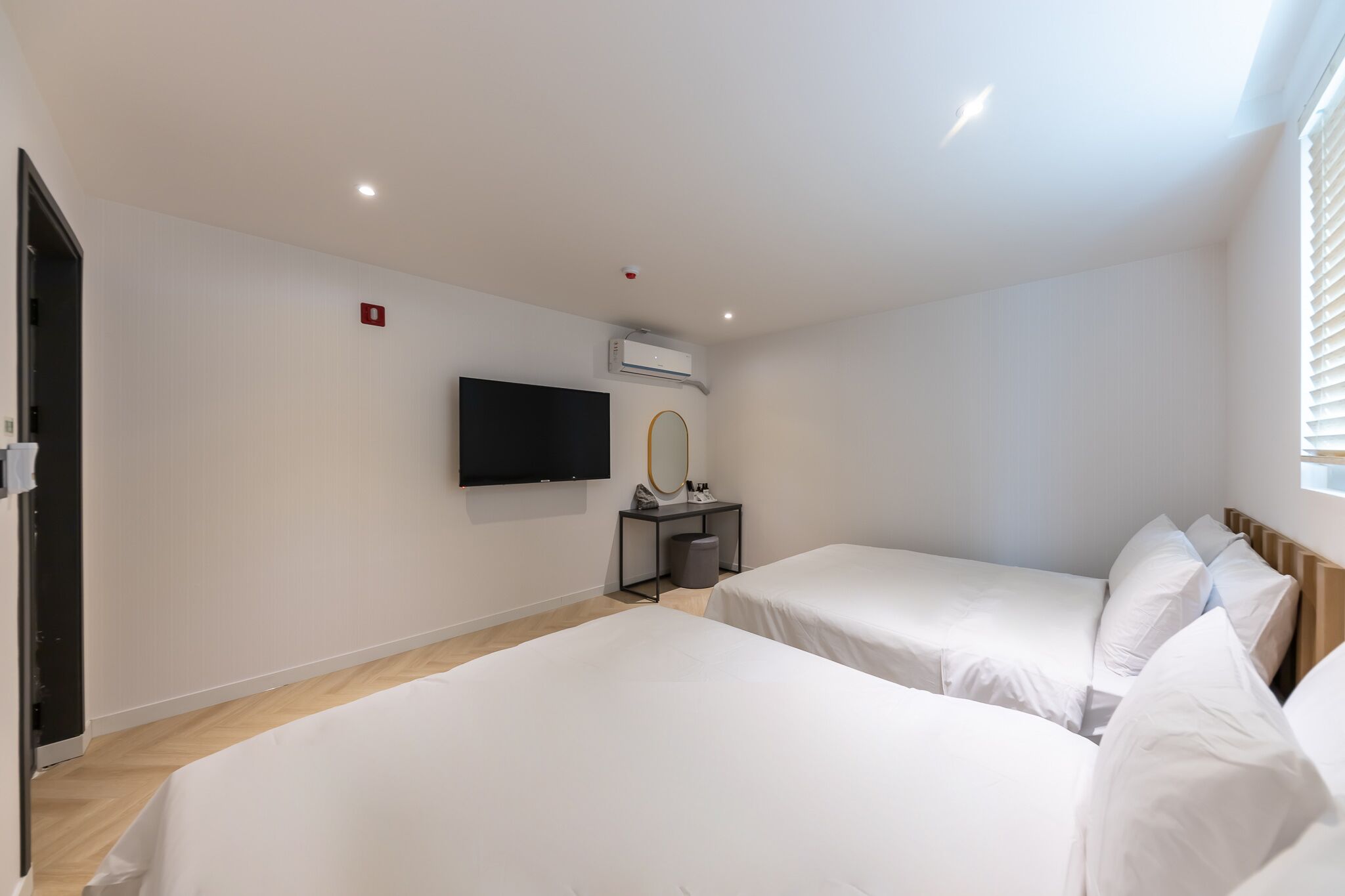 Een hotelkamer met twee bedden, een televisie, een spiegel en een airconditioner.