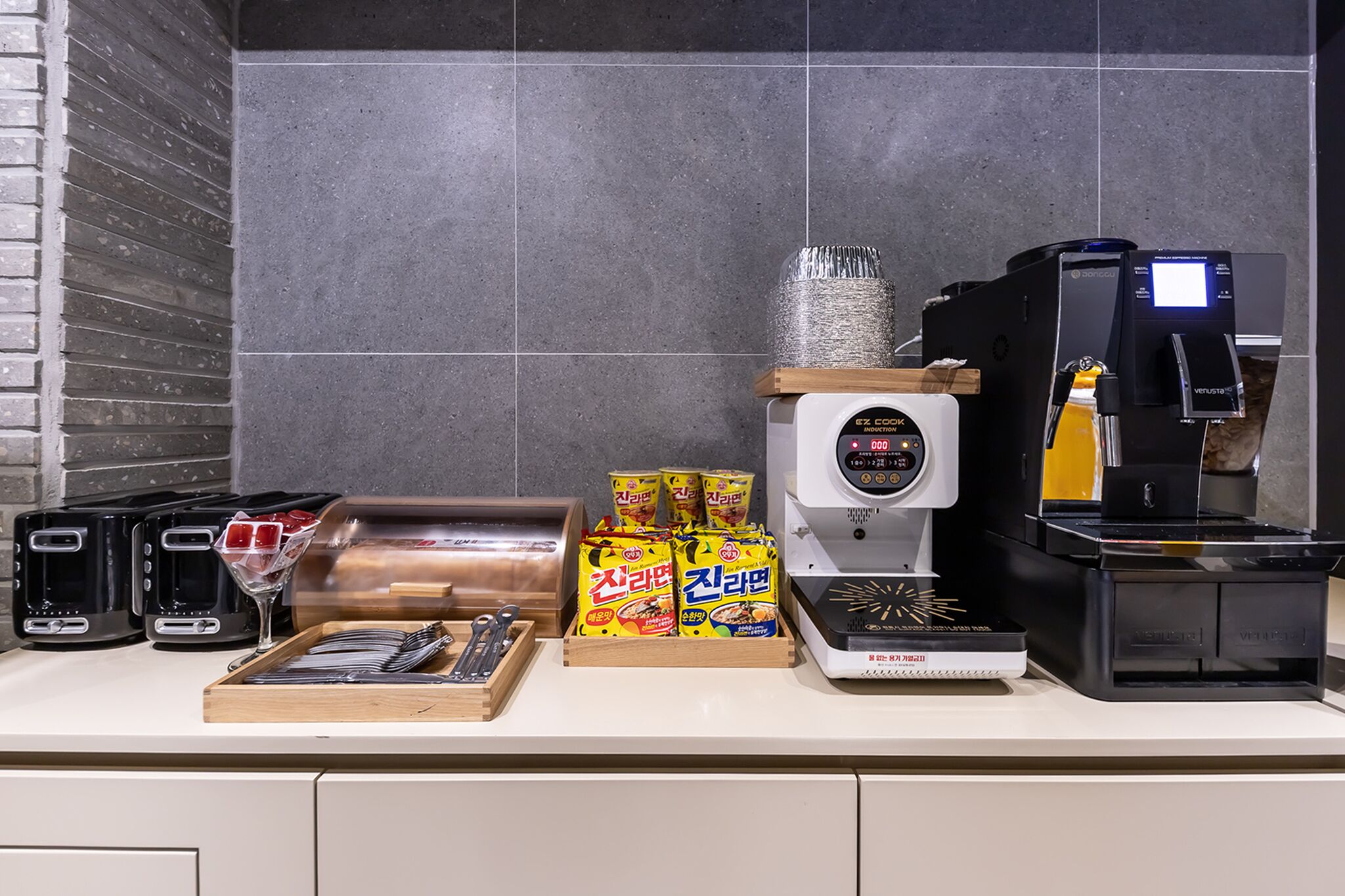 Una encimera de cocina con una cafetera, un tostador, un panero y aperitivos empaquetados.