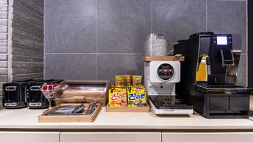 Una encimera de cocina con una cafetera, un tostador, un panero y aperitivos empaquetados.