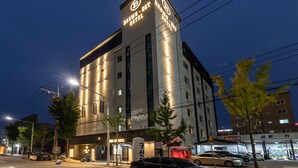 A modern hotel with a prominent sign, multiple floors, and a well-lit facade.