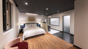 A modern hotel room with a large bed, bedside tables, a desk, and a chair.