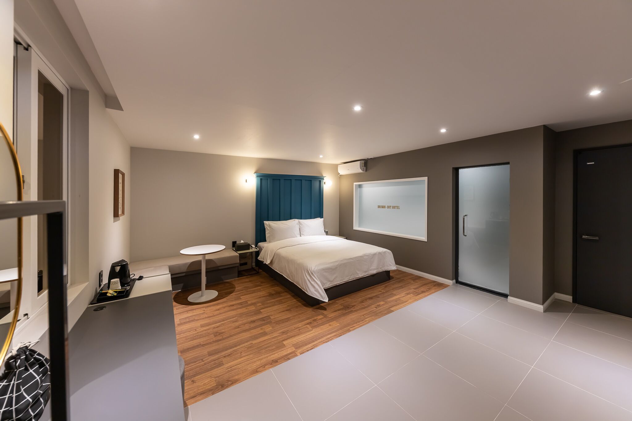 Una habitación de hotel moderna con cama, mesita de noche y una pequeña mesa redonda.