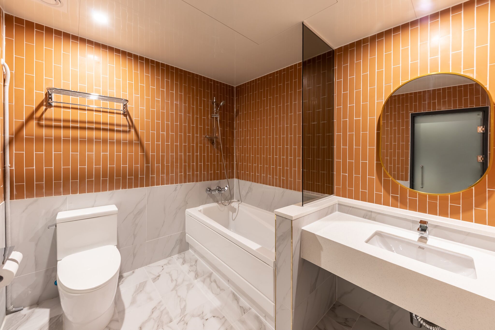 Un baño moderno con inodoro blanco, bañera y lavabo.
