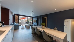 A modern kitchen with a white countertop, a dining area with a white table and grey chairs, and a large window with a view of the outside.