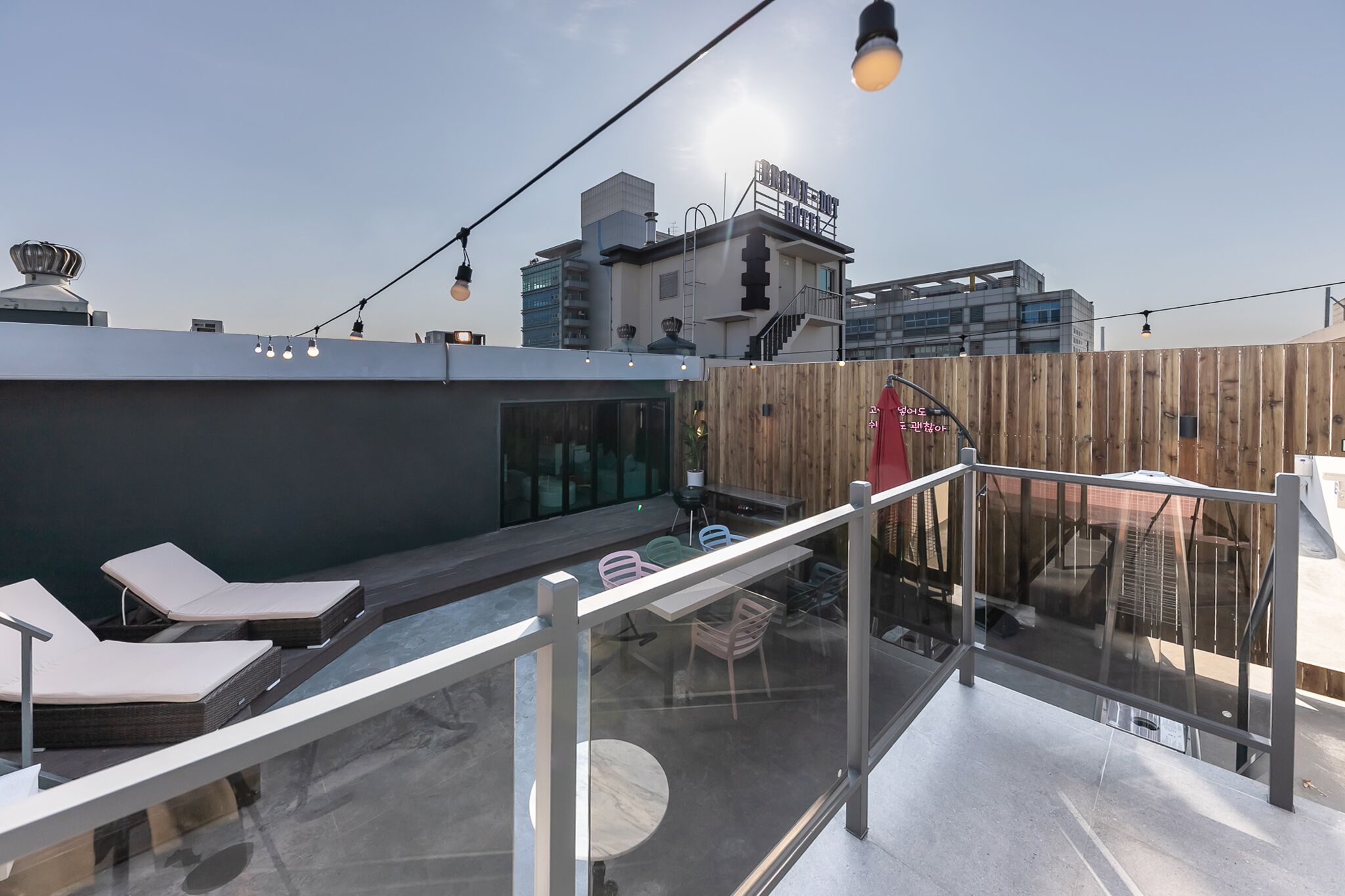 Una terraza en la azotea con sillones de descanso, barandilla de vidrio y vistas de la ciudad.