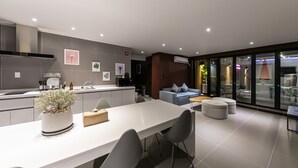 A modern kitchen with a dining area, grey tiles, and a large window.