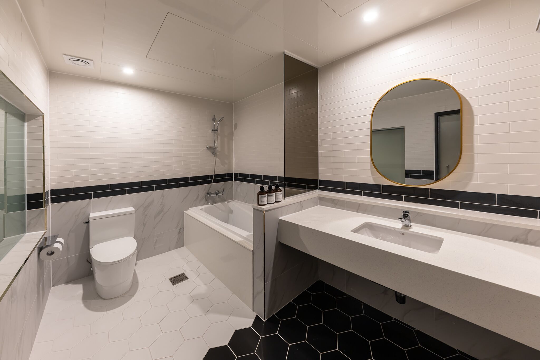 Un baño moderno con inodoro, bañera y dos lavamanos.