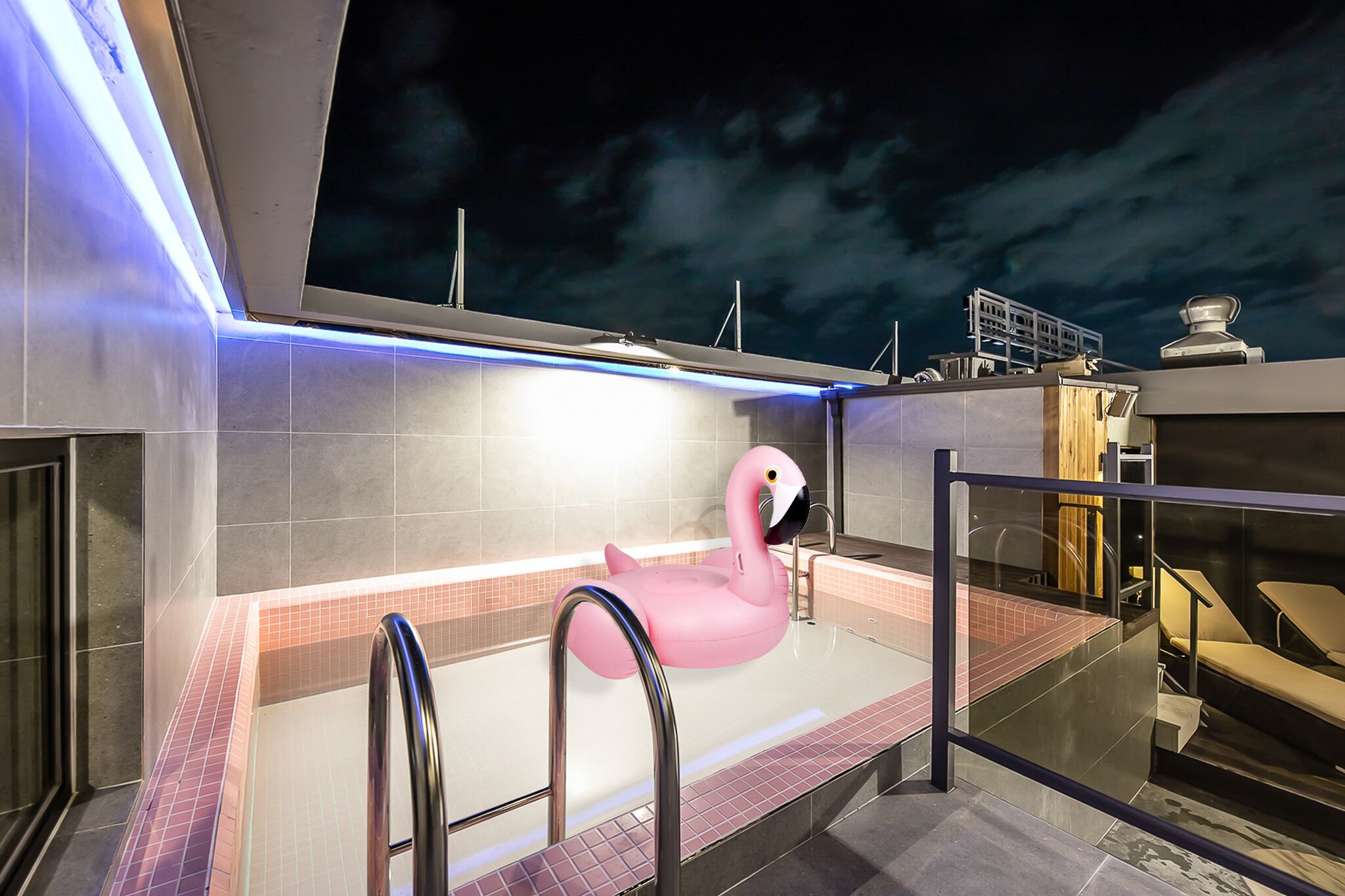 A modern bathroom with a pink flamingo float, a glass-enclosed shower area, and a view of the sky.
