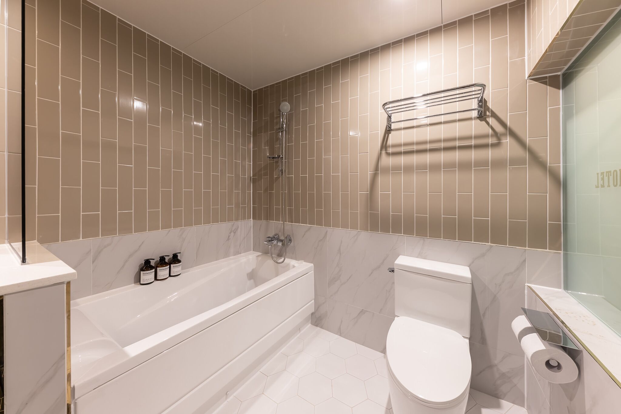 A modern bathroom with a bathtub, toilet, and a glass shower enclosure.