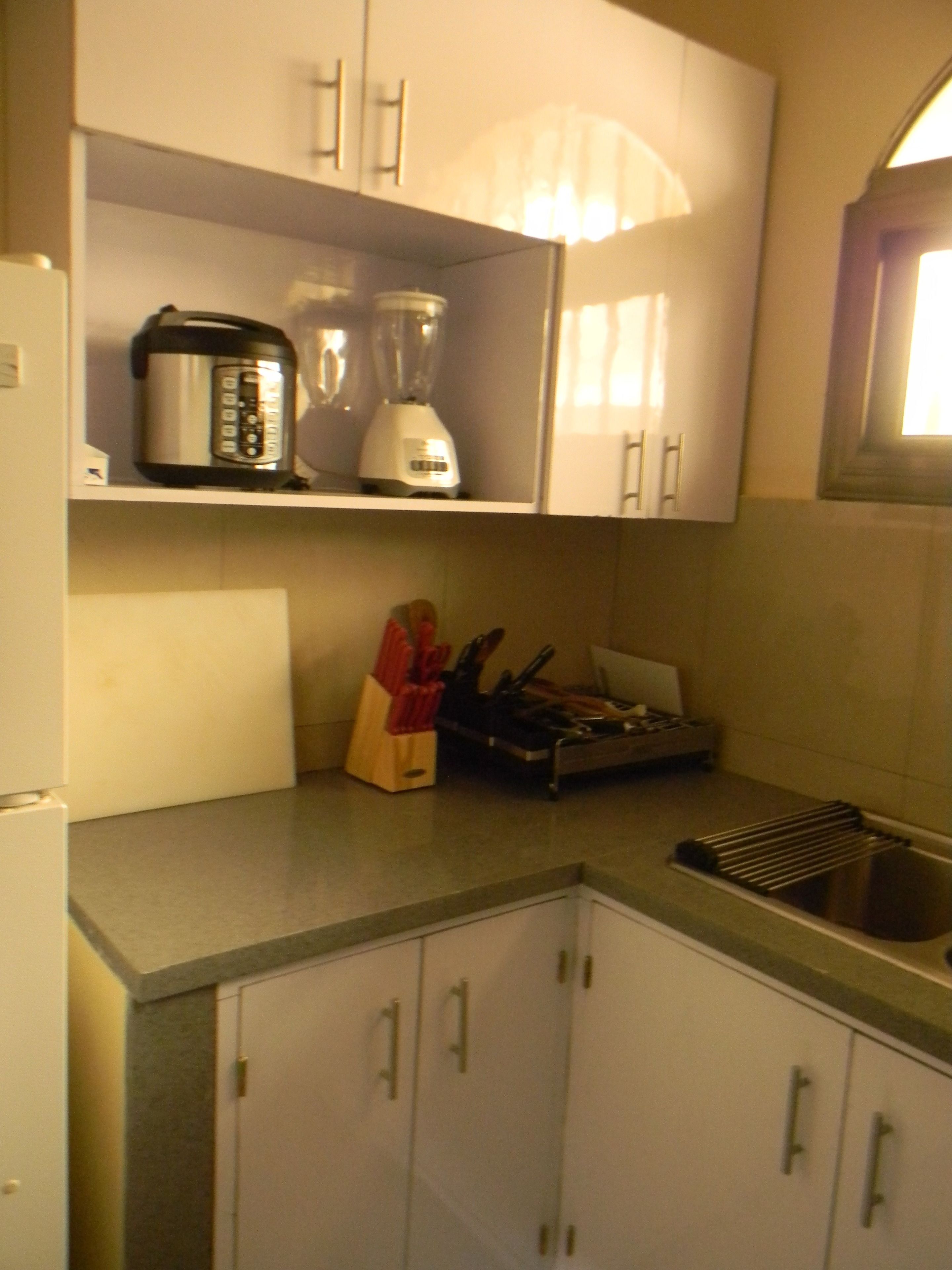 A kitchen with white cabinets, a countertop, a rice cooker, a blender, and a knife block.