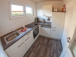 A kitchen with a sink, stove, and cabinets.