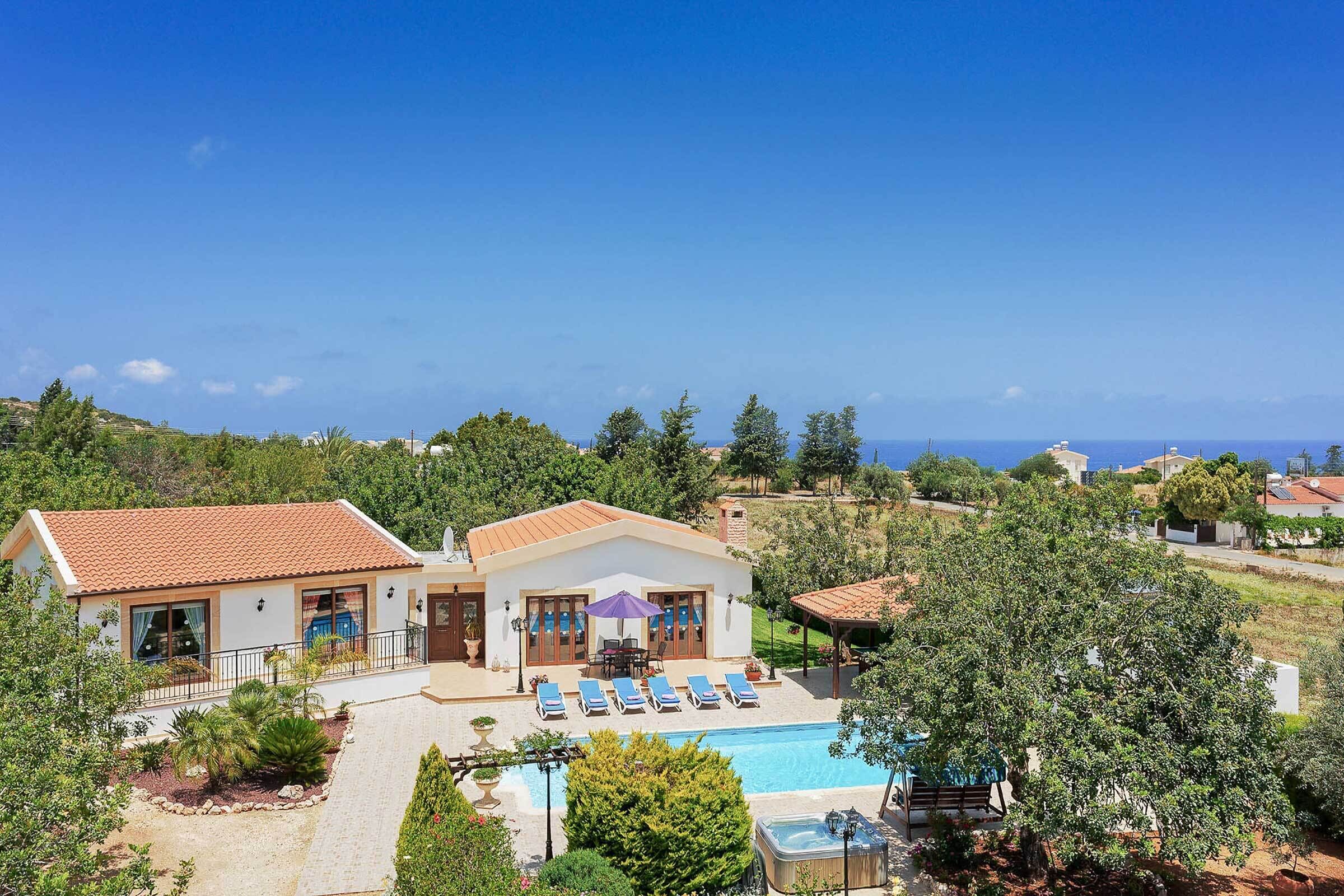 Ein zweistöckiges Haus mit Swimmingpool, Sitzgelegenheiten im Freien und Meerblick.