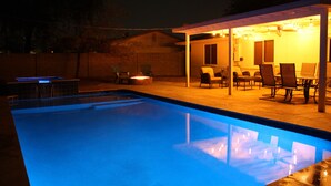 Ein Schwimmbecken mit überdachter Terrasse und Sitzgelegenheiten im Freien.