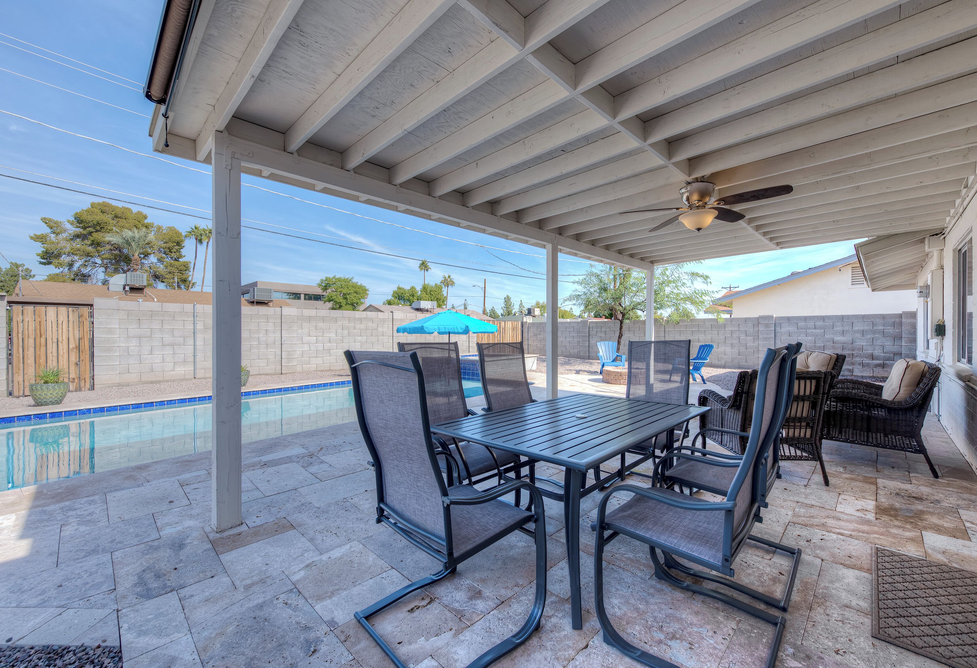 A covered patio with a pool table, chairs, and a ceiling fan.