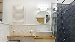 A modern bathroom with a white toilet, a sink with a wooden countertop, a mirror, and a shower with a black patterned wall. - Smart Casual Riga Center Apartment (Centra rajons)