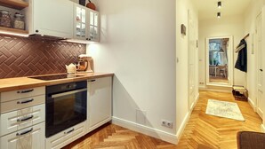 A modern kitchen with white cabinetry, a herringbone-patterned backsplash, and a wooden countertop. There is a built-in oven and a dishwasher. - Smart Casual Riga Center Apartment (Centra rajons)