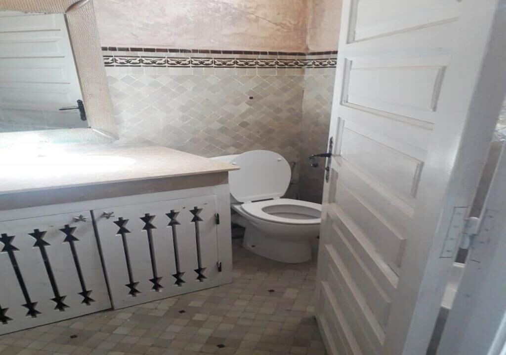 Een badkamer met een betegelde vloer, toilet in het wit en een wastafel met decor kastje.