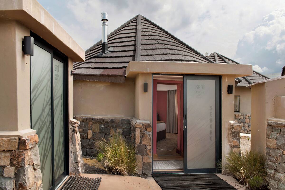 A modern building with a stone exterior, a sloped roof, and a glass door leading to a room.