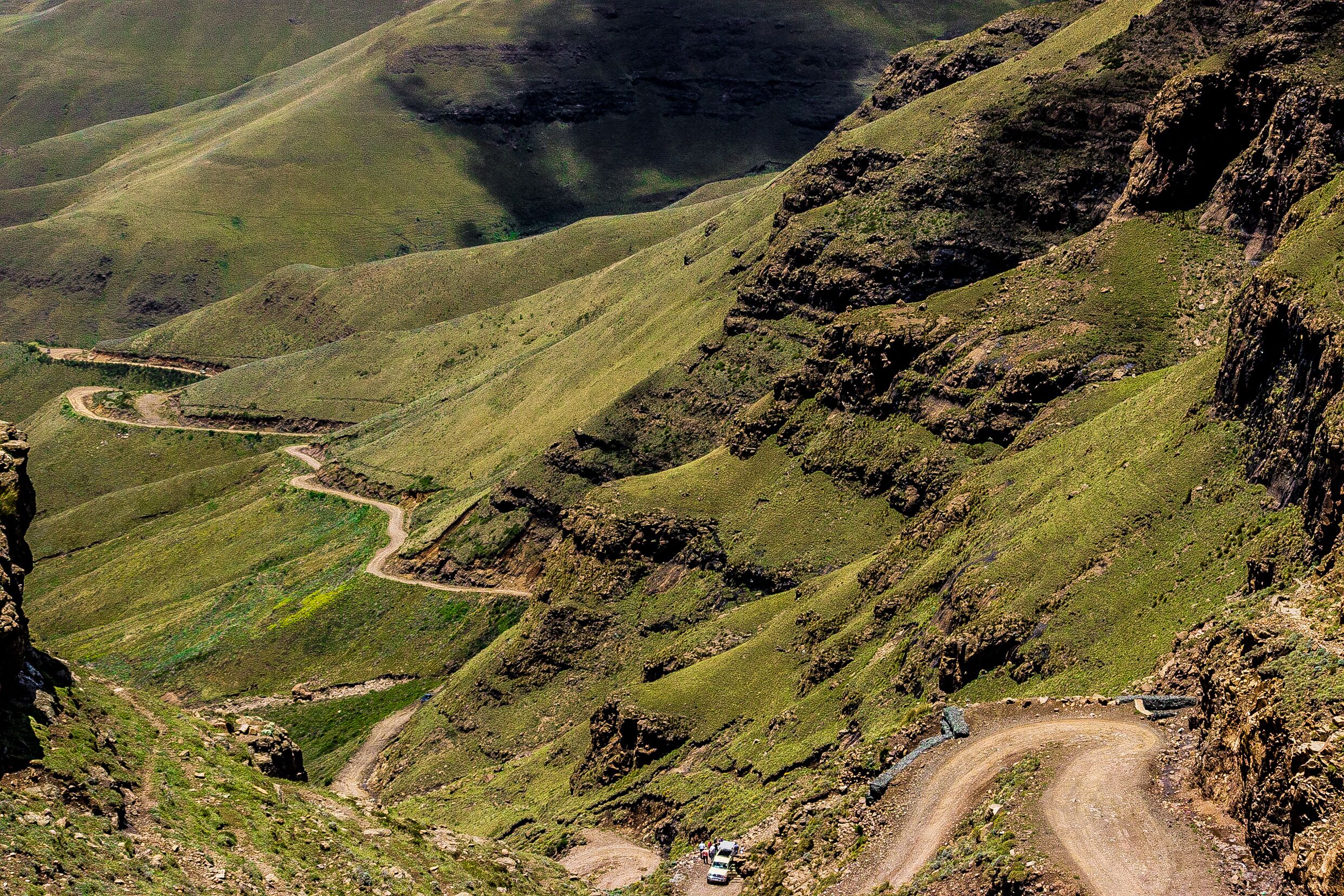 Una carretera sinuosa en la montaña, con un vehículo y una persona.