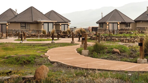 A resort with multiple buildings, a winding pathway, and natural landscaping. - Sani Mountain Lodge (Sani Pass)