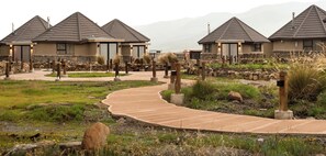 A resort with multiple buildings, a winding pathway, and natural landscaping. - Sani Mountain Lodge (Sani Pass)