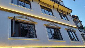 Fachada de edificio con varias ventanas, algunas con contraventanas, y un letrero que indica un nombre de empresa.