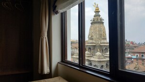 Una habitación con ventana que da a un templo con una aguja dorada.