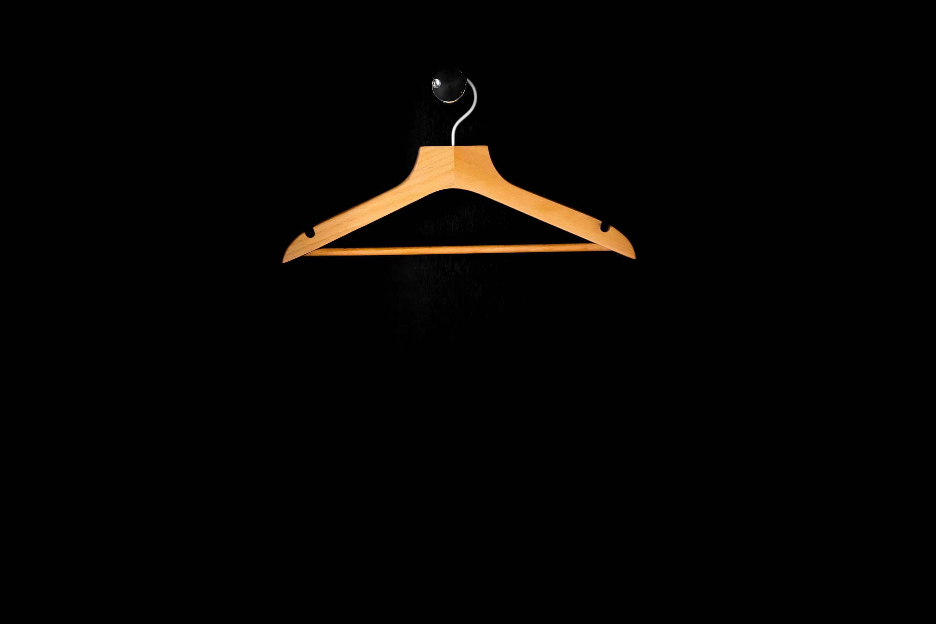 A wooden hanger against a black background.