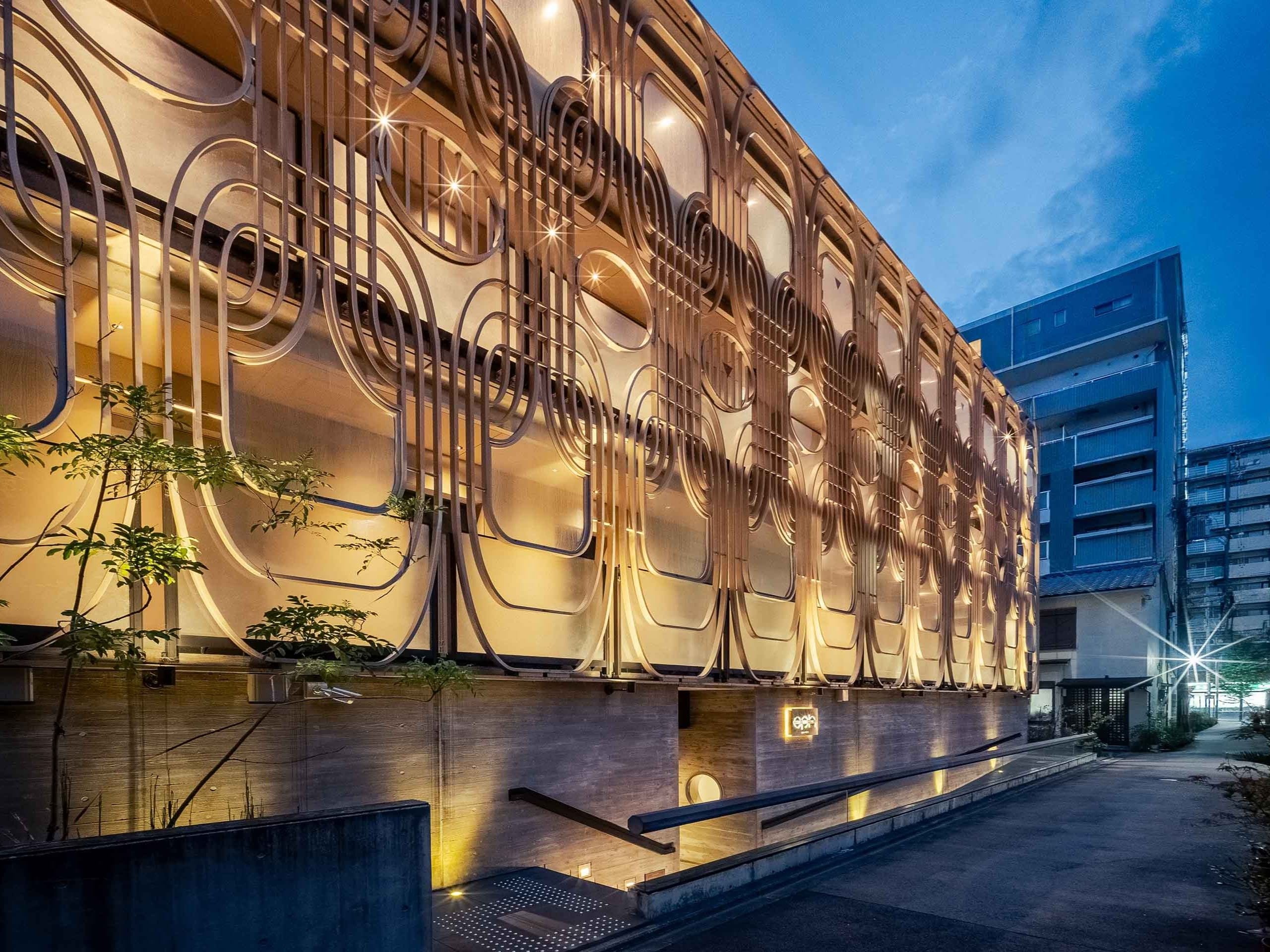 Um edifício moderno com fachada singular, destacando padrões geométricos e iluminação embutida.