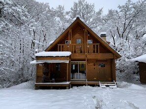 A wooden cabin with a balcony, surrounded by snow-covered trees. - BETSUINN (Hakuba)