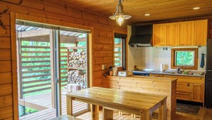 Een houten vakantiehuis met een keuken, een eettafel en een bank.