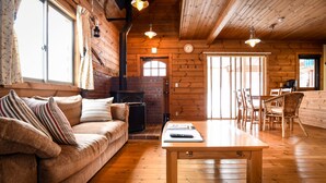 Een gezellig interieur van een chalet met een bank, een houten tafel en een open haard.