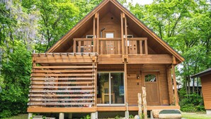 Een houten chalet met een balkon, grote ramen en een deur met ruit.