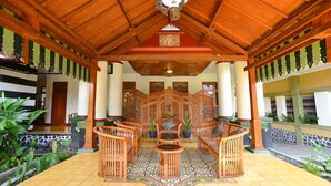 A covered outdoor seating area with wooden furniture and a decorative ceiling. - Kotagede Heritage Homestay (Yogyakarta)