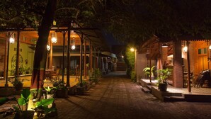 A nighttime view of a courtyard with a covered seating area and potted plants. - Kotagede Heritage Homestay (Yogyakarta)