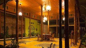 A covered outdoor area with a tiled floor, a table with chairs, and hanging light fixtures. - Kotagede Heritage Homestay (Yogyakarta)