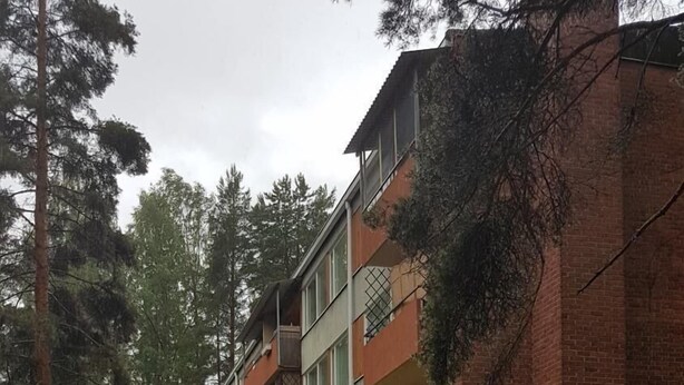 En grussti, der fører hen til en høj boligbygning med altaner.