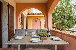 A dining area with a table set for four, a potted plant, and a bottle of wine.