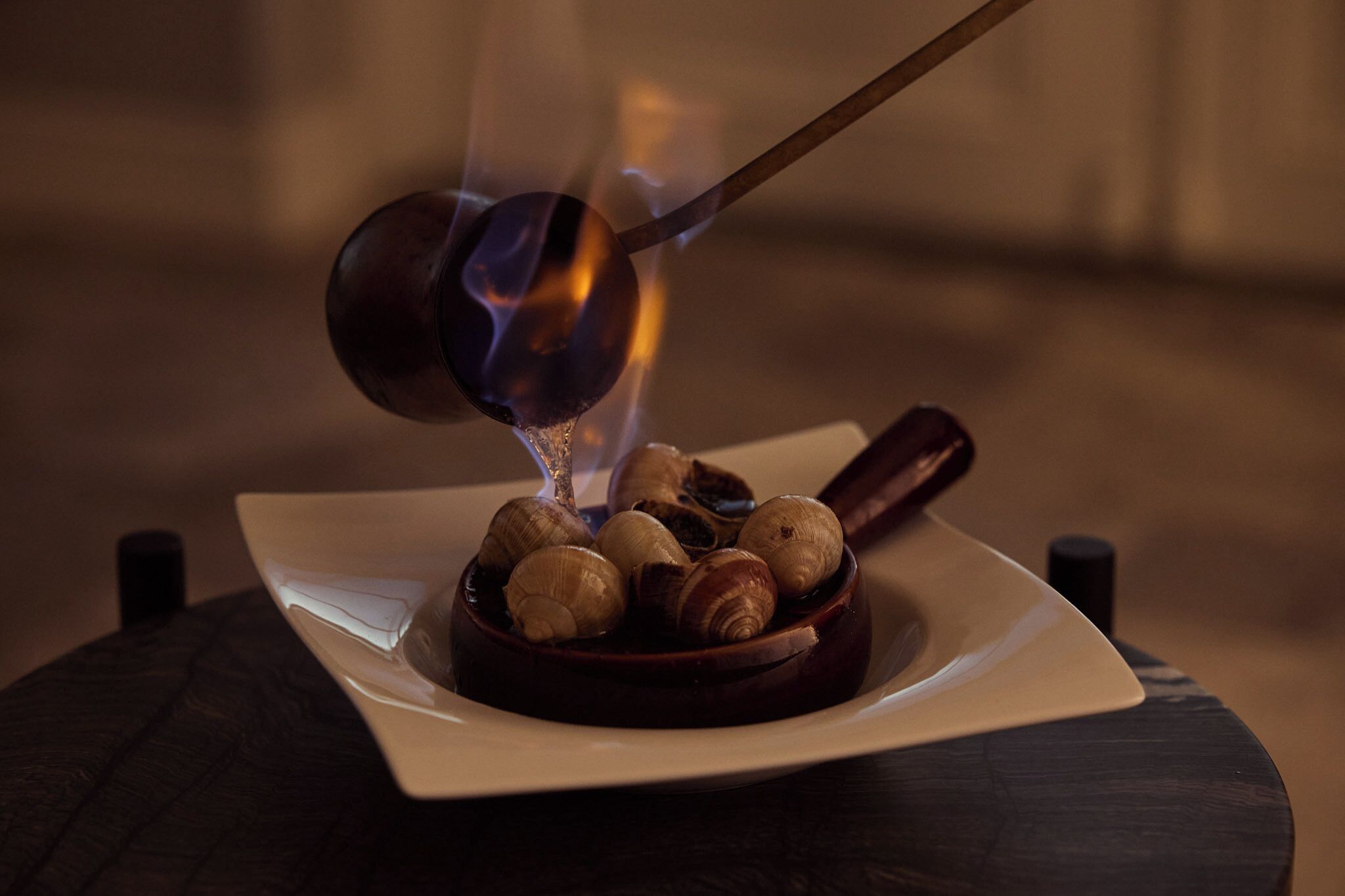 A dish of snails being cooked with a spoon.
