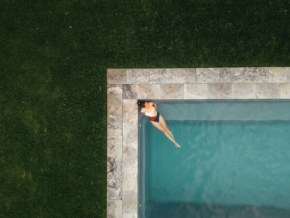 A swimming pool with a tiled edge, surrounded by a grassy area. - Le Mas Barossa Valley (Rowland Flat)