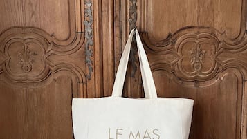A white tote bag hanging on a wooden door with carved designs.