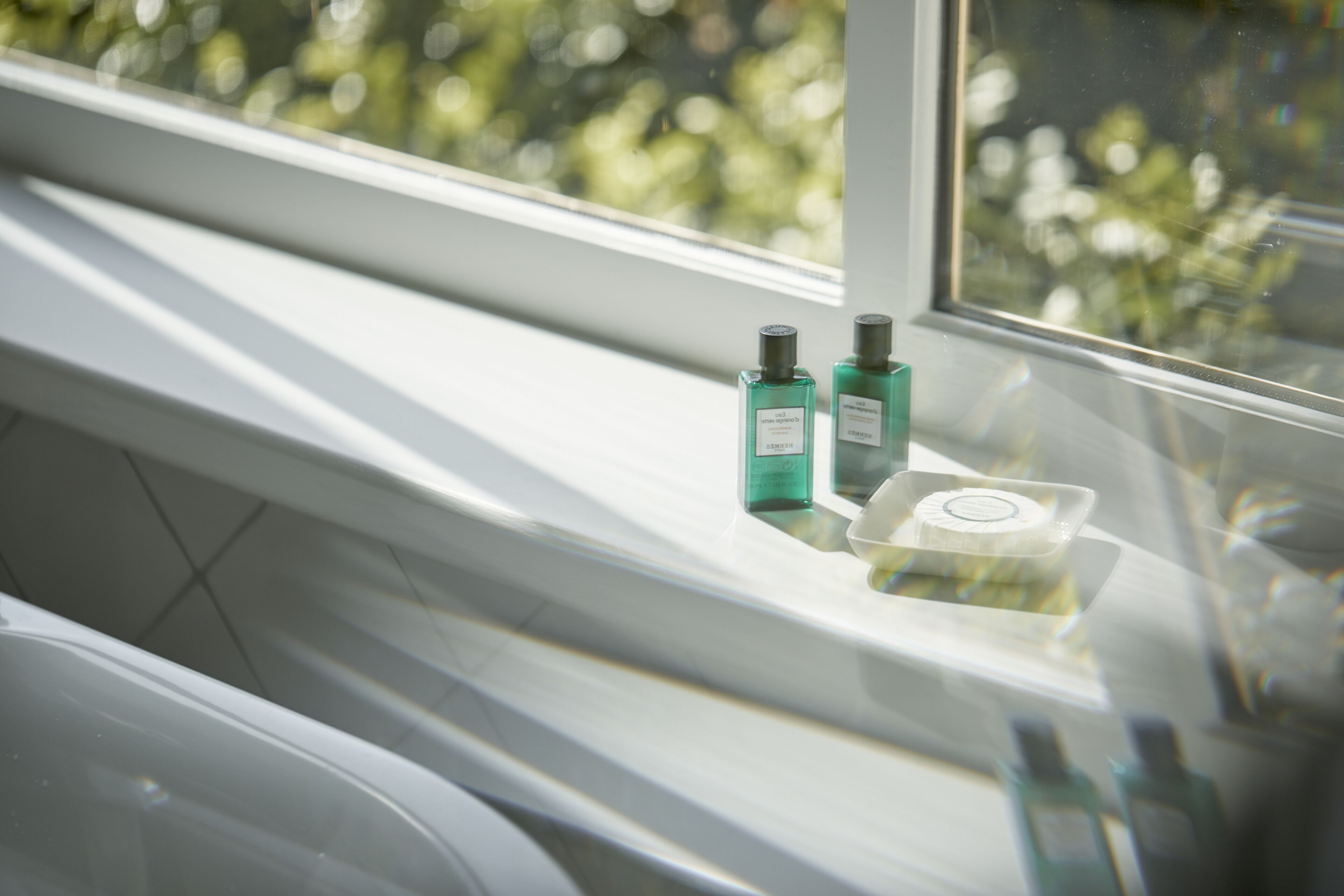 A bathroom with a window, a sink, and two bottles of liquid on the windowsill.