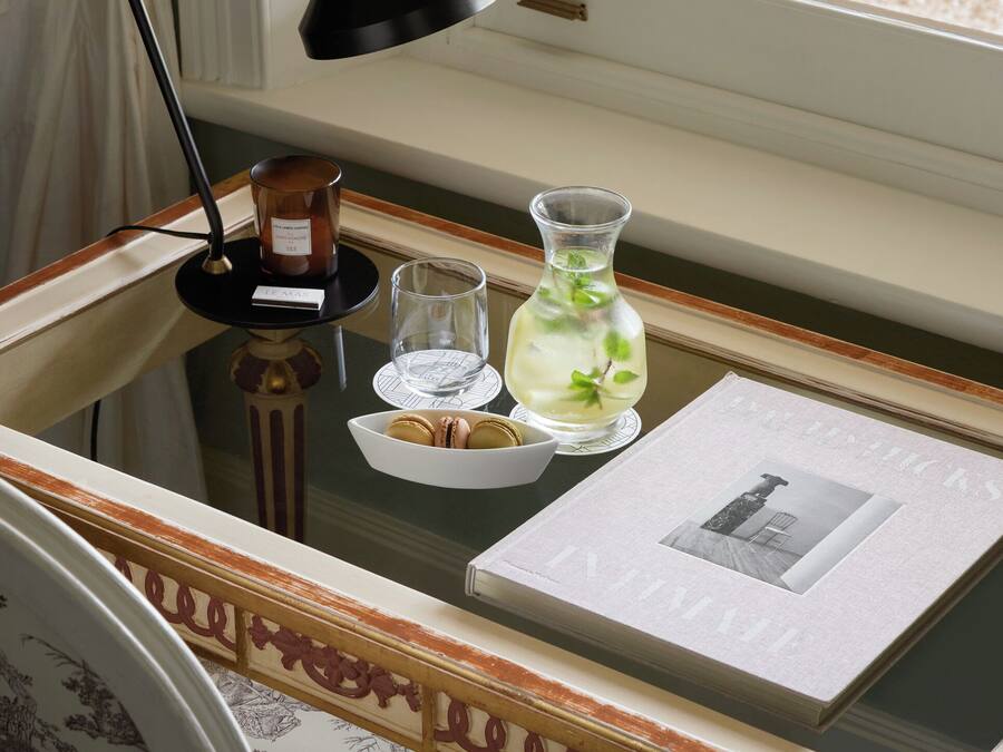 A desk with a lamp, a vase, a glass, and a framed picture.